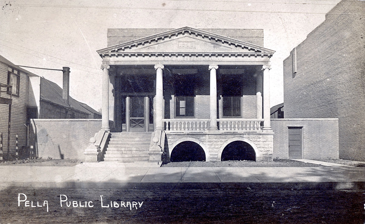 A black and white photo of a library with the text "Pella Public Library" written in the corner.