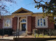 Red bricked library with small columns and two arched windows.