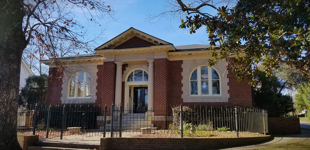 Red bricked library with small columns and two arched windows.