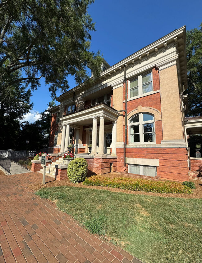 A red bright library with flat roof and columns, before a brick path