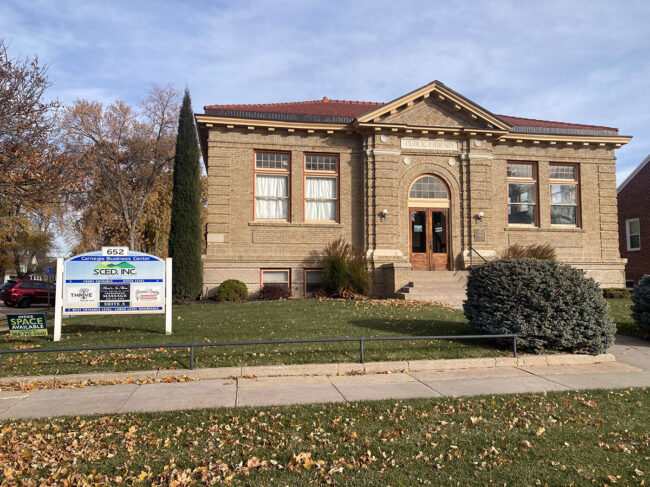 A stone library on a lawn, with a sign to the left.