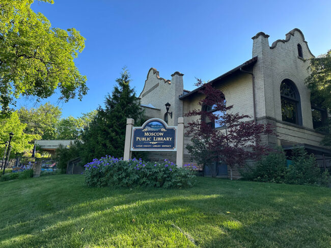 A library and sign on a grass lawn with trees