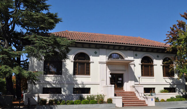 A stucco library with a red roof.