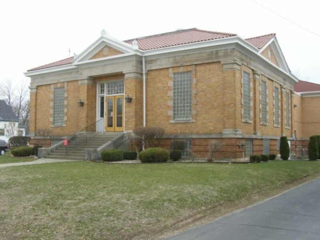 A yellow brick library building on a lawn.