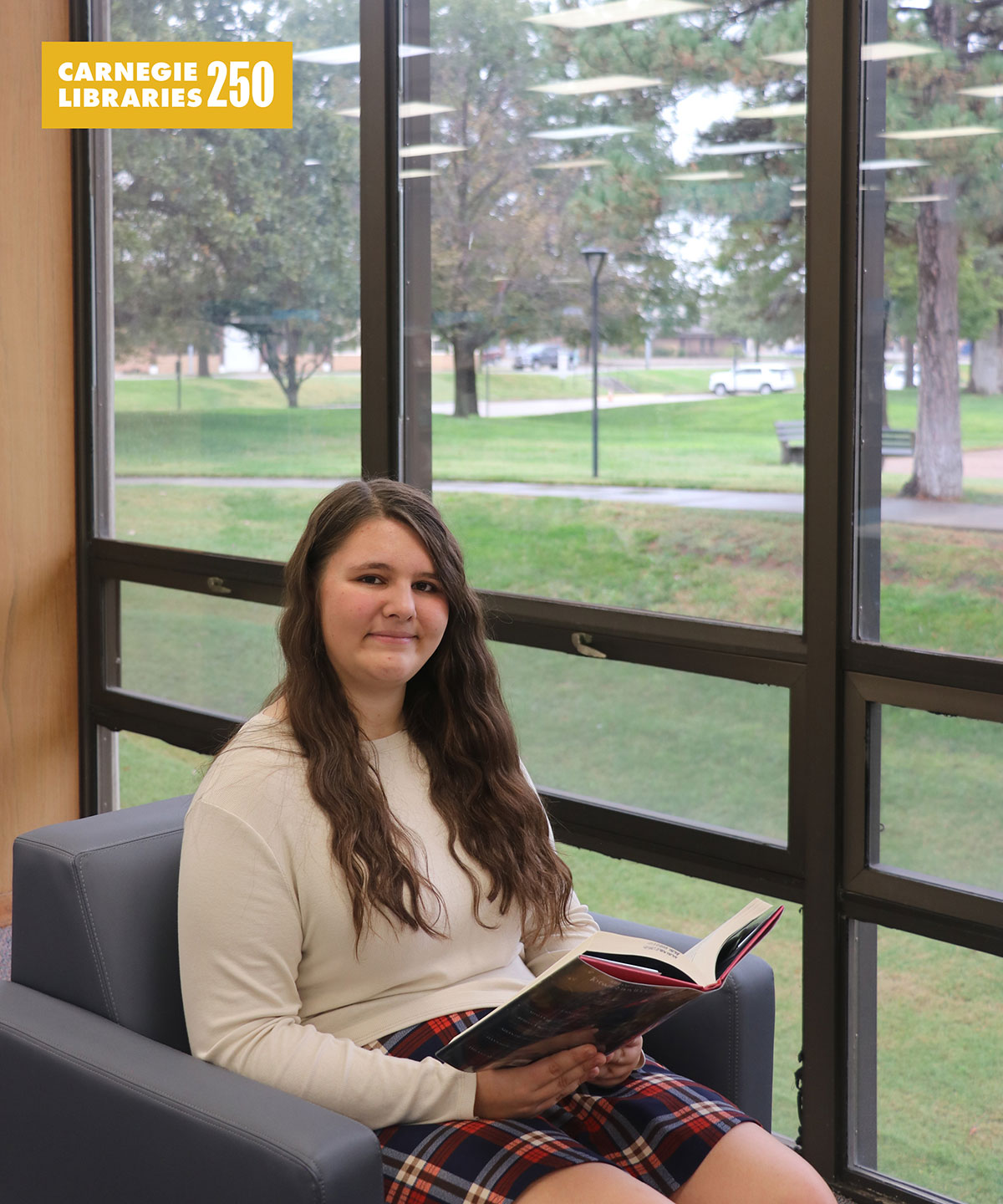 A girl sits by a window reading