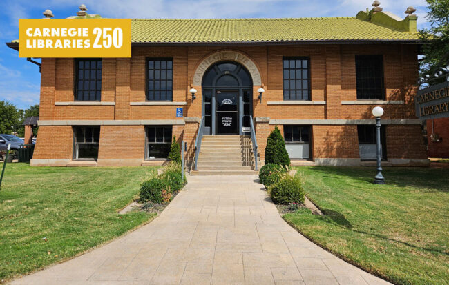 A red brick library with rectangular windows and a green lawn.