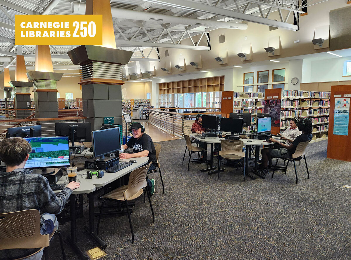 People sit at computers in an open lab space in a library.