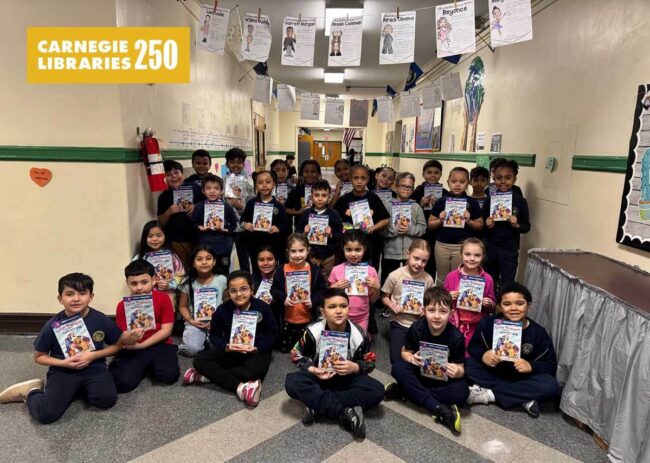 Children sit in rows holding a picture book on George Washington